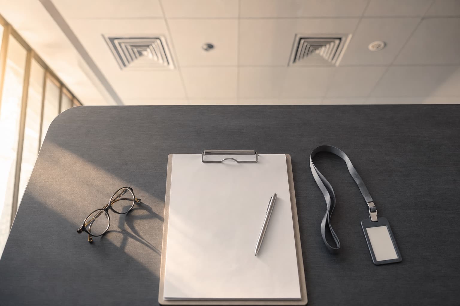 Prancheta com formulário de registro sobre mesa de escritório, com difusores de ar no forro ao fundo